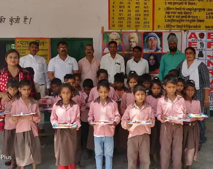Children in school uniform holding stationery from the Trust at a government school in Jewar