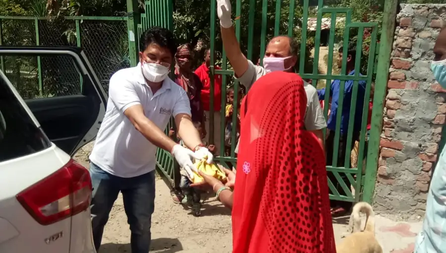 A masked volunteer hands a food packet to a woman during the 2020 lockdown